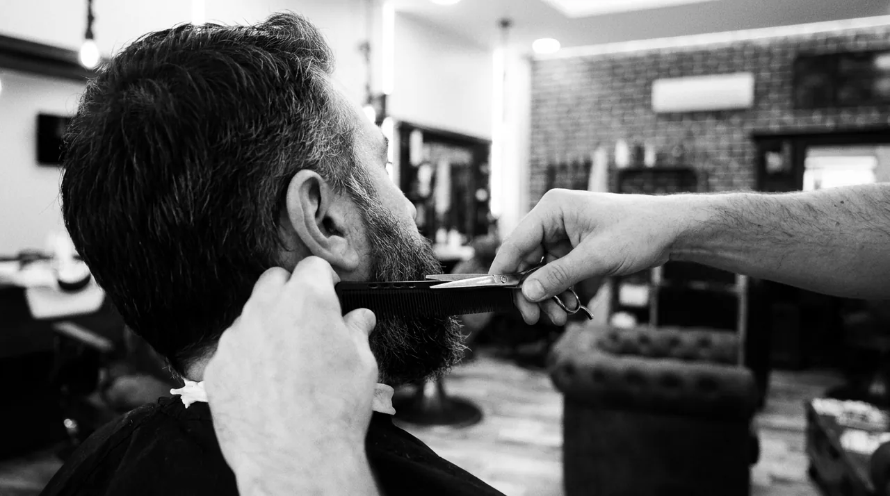 Par-dessus l'épaule : peigne et ciseaux égalisent la barbe là où elle rejoint le dégradé