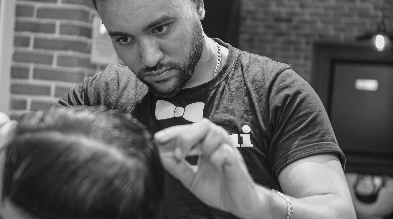 Barbier Lui Coiffeur en train de couper les cheveux d'un client aux ciseaux