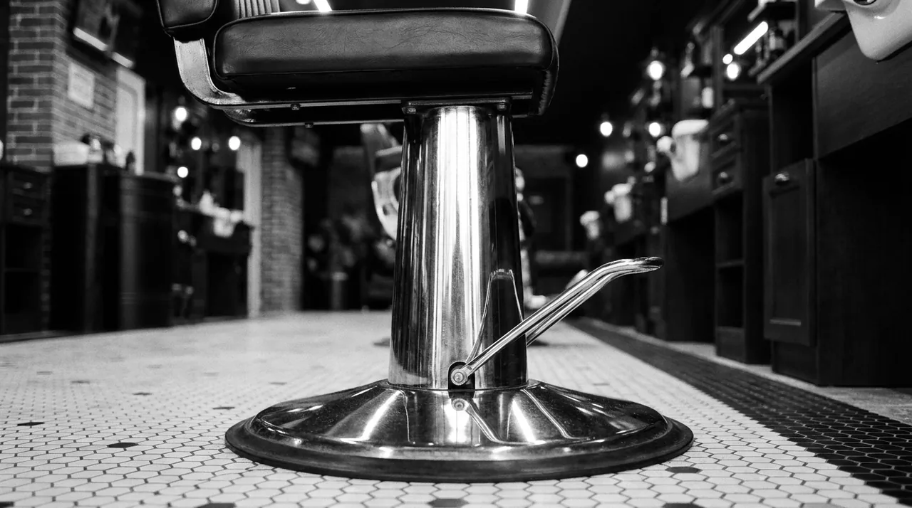 Pied chromé d'un fauteuil de barbier ancien et sa pédale de pompe, sur carrelage