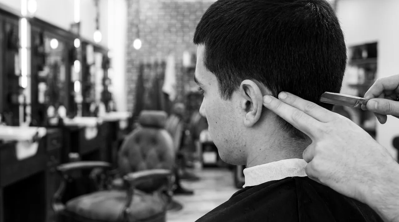 Par-dessus l'épaule, un rasoir trace le contour des cheveux derrière l'oreille