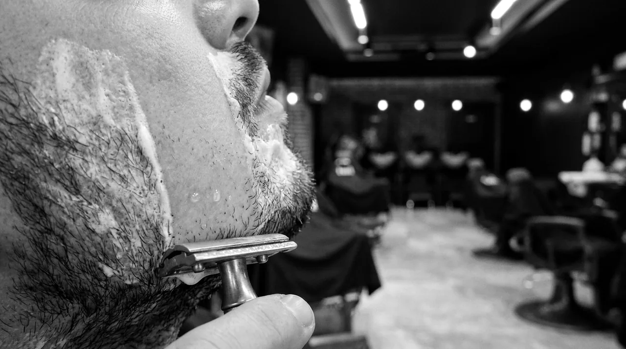Tête de rasoir de sûreté traçant un sillon net dans la mousse, sur une joue