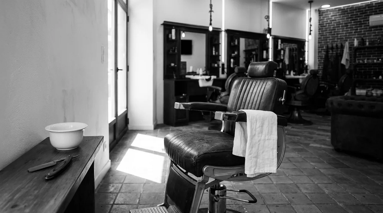 Salon de barbier vide, un fauteuil en cuir avec un linge blanc plié sur l'accoudoir