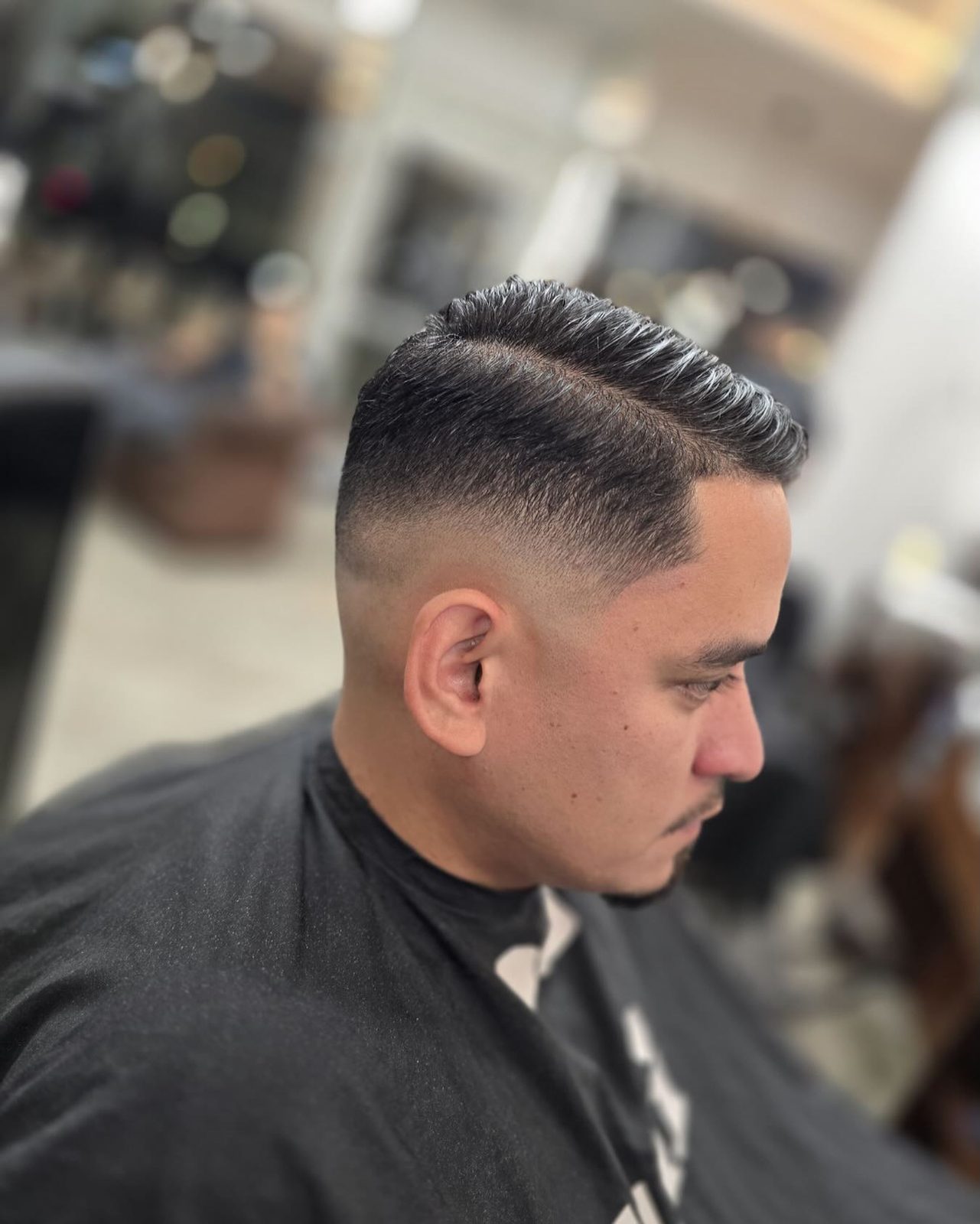 Coupe homme pompadour avec skin fade et raie nette