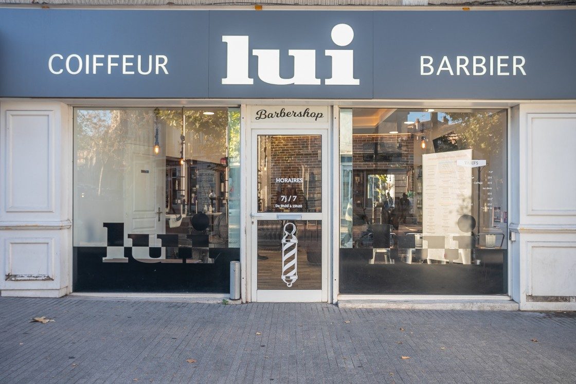 Devanture du barbershop Lui Coiffeur à Draguignan : enseigne Coiffeur Barbier et barber pole à l’entrée