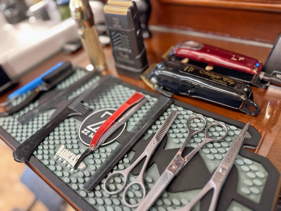 Outils du barbier : ciseaux, tondeuse et rasoir droit sur le poste de travail