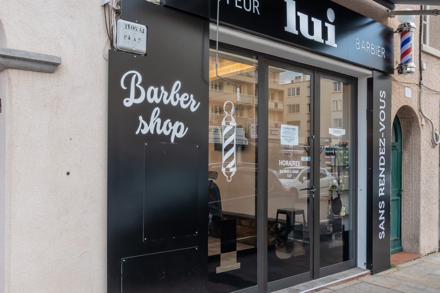 Façade noire du salon Lui Coiffeur rue Pierre-Curie à Sainte-Maxime, poteau de barbier et inscription Sans rendez-vous