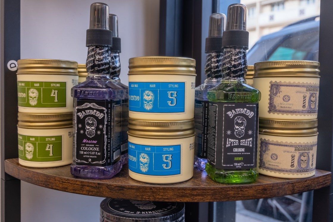 Pots de cire et flacons d’eau de Cologne et after-shave Bandido sur une étagère du salon Lui Coiffeur à Sainte-Maxime